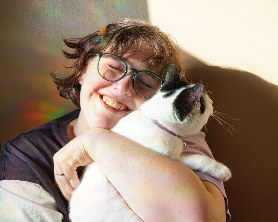Person holding a cat with a rainbow light effect